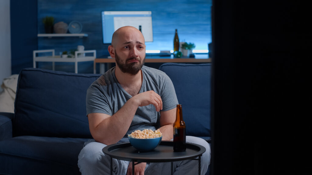 Sad guy watching drama movie on TV crying