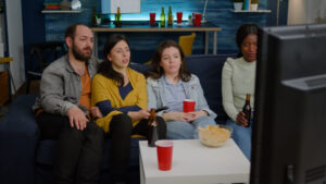 Multi-racial friends changing channels on television until find funny movie