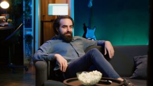 Overjoyed man sitting on couch laughing while watching funny comedy movie