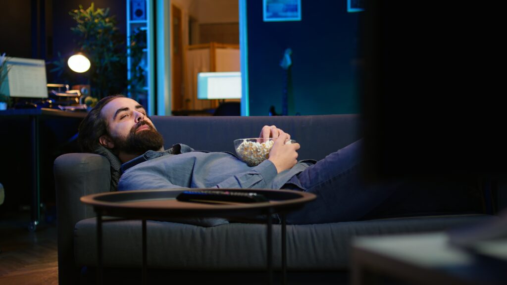 Upbeat homeowner laying down on couch watching feel good movies on TV