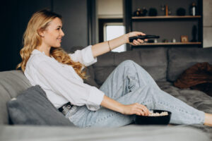 Woman eating popcorn at home on couch and watching movie